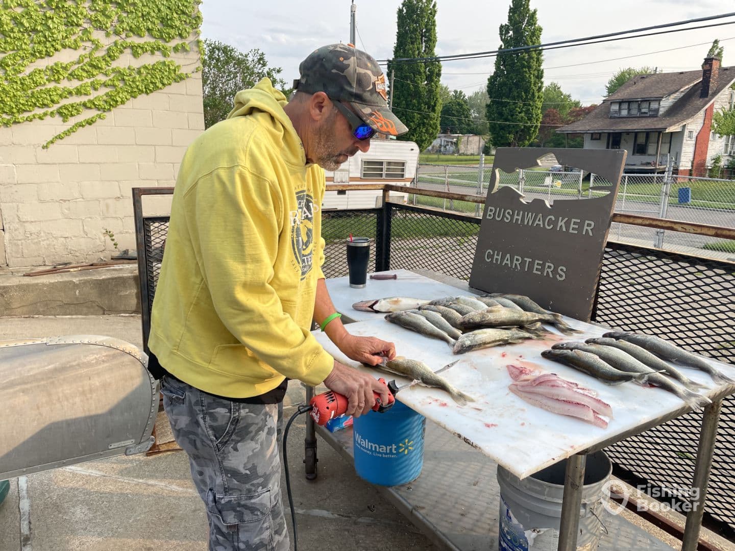 A fisherman filleting fish at a cleaning station, showcasing a variety of catches including fresh fillets, after a successful charter trip.