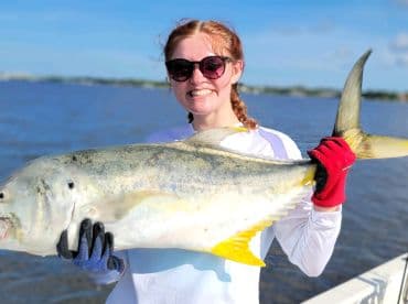 Young angler proudly holding a large Jack Crevalle while fishing in a coastal environment.