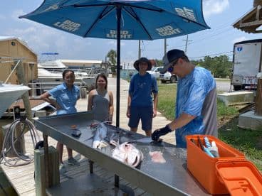 Group of anglers at a cleaning station, showcasing a variety of fish after a successful day on the water.