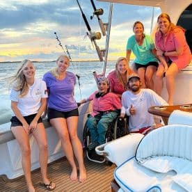 A cheerful group of anglers enjoying their time on a fishing boat, showcasing a vibrant sunset backdrop and a welcoming atmosphere.