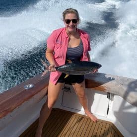 A proud angler displaying a large Yellowfin Tuna aboard a sportfishing boat, showcasing the excitement of deep-sea fishing.