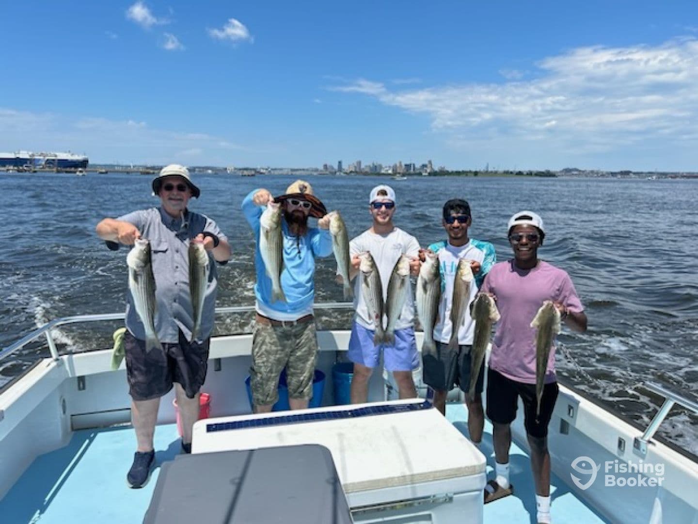 Group of anglers proudly displaying their catch of striped bass while on a boat, enjoying a sunny day on the water.