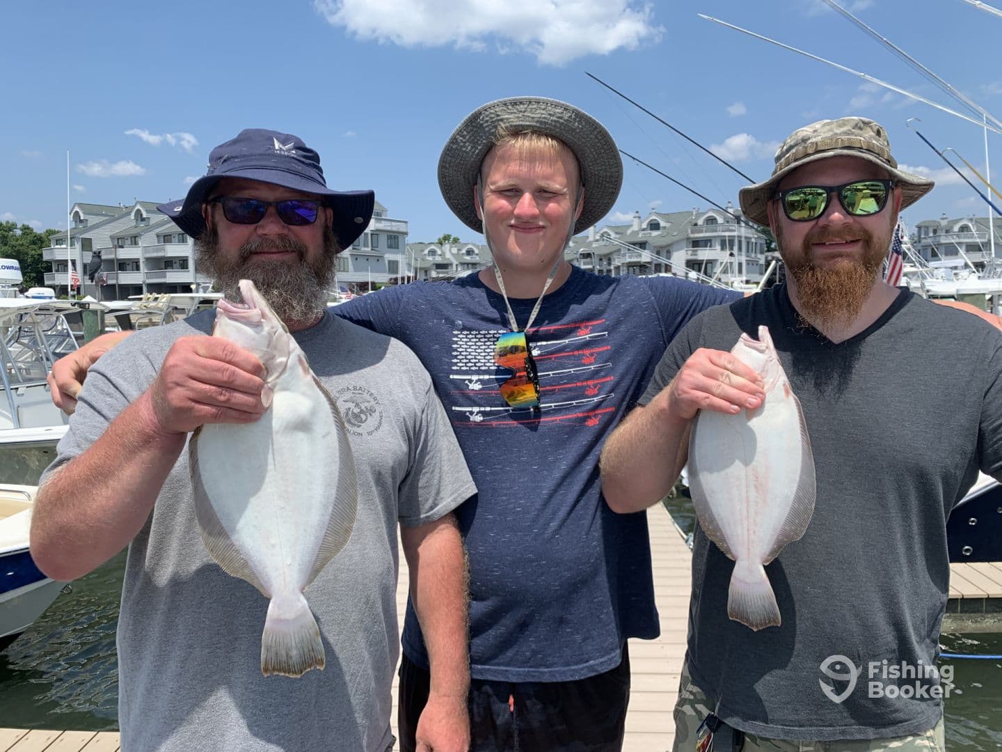 Three anglers proudly displaying their catch of Flounder at the marina, showcasing a successful day of fishing.