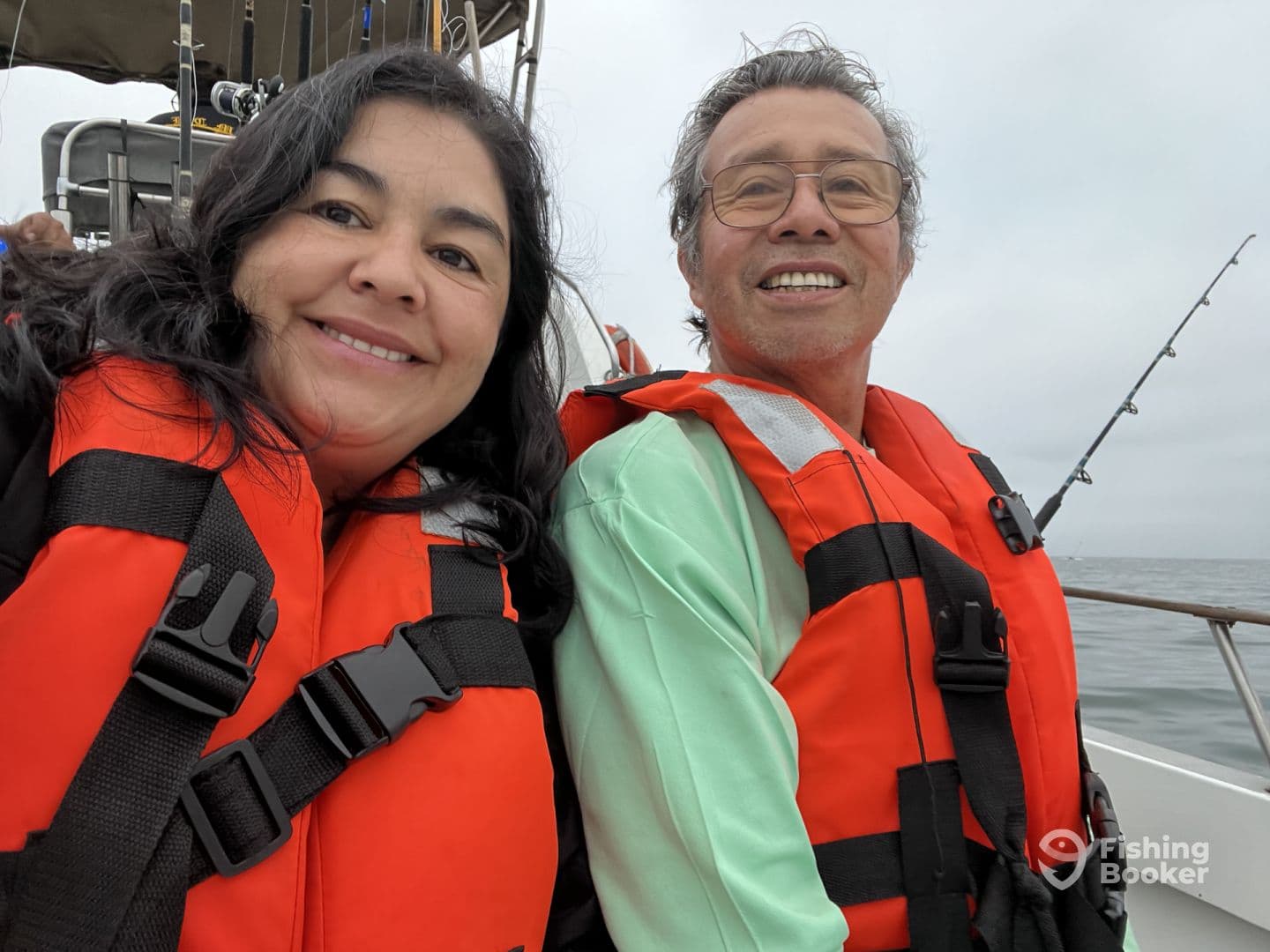 Two anglers enjoying a day on the water, wearing life jackets while seated on the boat, with fishing rods visible in the background.