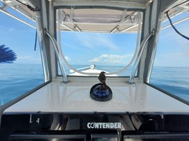 Interior view of a Contender boat's helm, showcasing the sleek design and clear blue skies over calm waters.