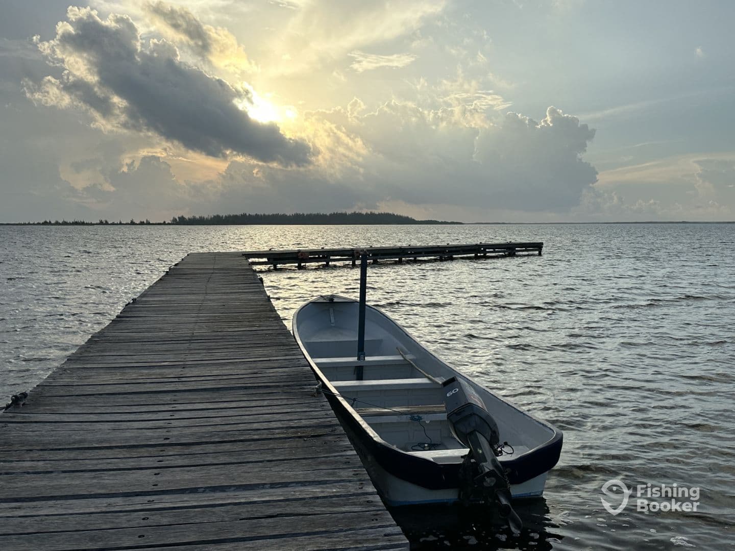 A serene view of a small boat docked at a wooden pier, set against a dramatic sunset over calm waters, ideal for fishing adventures.