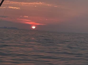 A serene sunset over the water, capturing the tranquil atmosphere of a fishing trip.