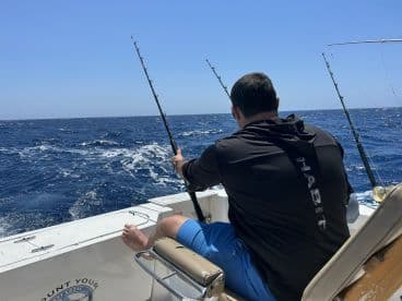 An angler actively casting a fishing rod while enjoying a day on the open ocean, showcasing the excitement of deep-sea fishing.