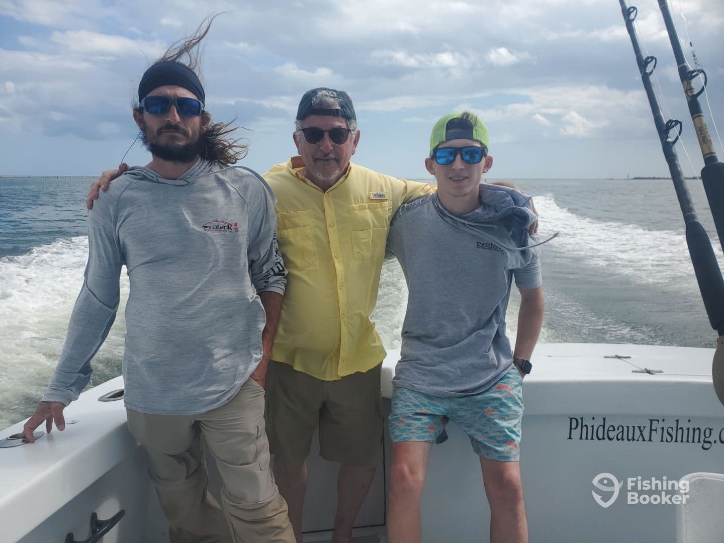 Three anglers posing on the side of a fishing boat, showcasing the vessel's name 'PhideauxFishing.com' against a backdrop of open water.