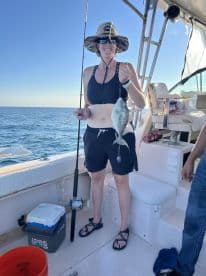 An angler proudly displaying a caught fish while fishing on a boat in open waters.