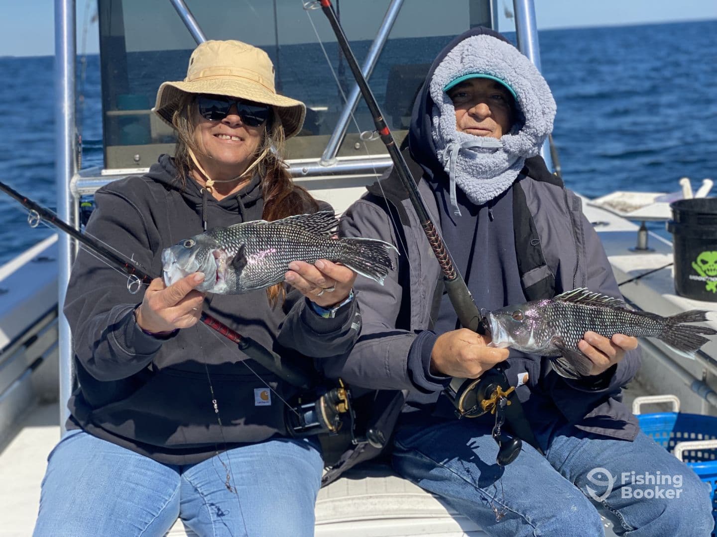 Two anglers proudly displaying their catches of Black Sea Bass while fishing offshore, showcasing a successful day on the water.