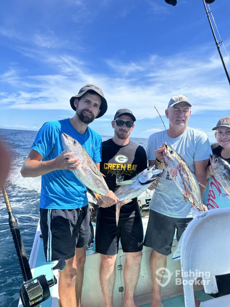 Group of anglers proudly displaying their catch of Yellowfin Tuna aboard a fishing charter in clear blue waters.