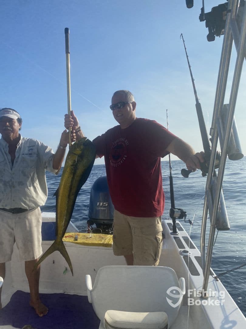 Two anglers proudly displaying a large Mahi Mahi on a fishing boat, showcasing a successful deep-sea fishing trip.