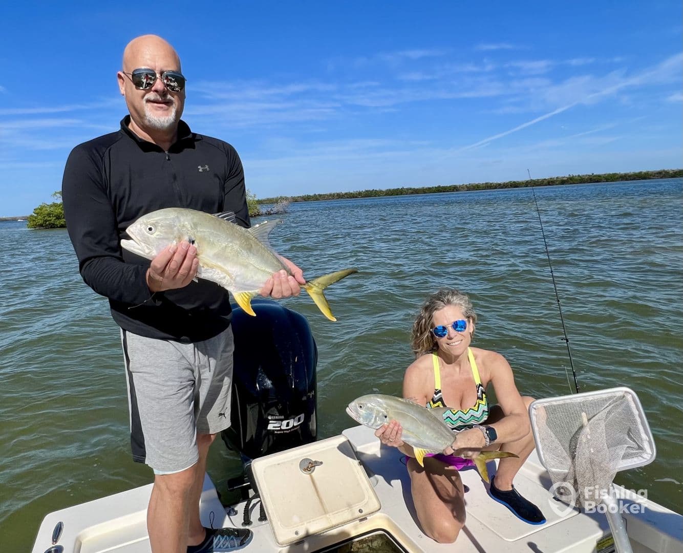 Two anglers proudly displaying their catches, a pair of Yellow Jacks, while enjoying a sunny day on the water.
