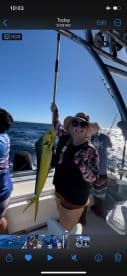 A proud angler holding a vibrant Mahi Mahi while fishing offshore, showcasing a successful day on the water.
