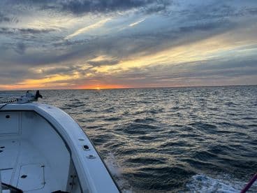 A scenic view of the boat's exterior during sunset, showcasing the calm waters and vibrant sky.