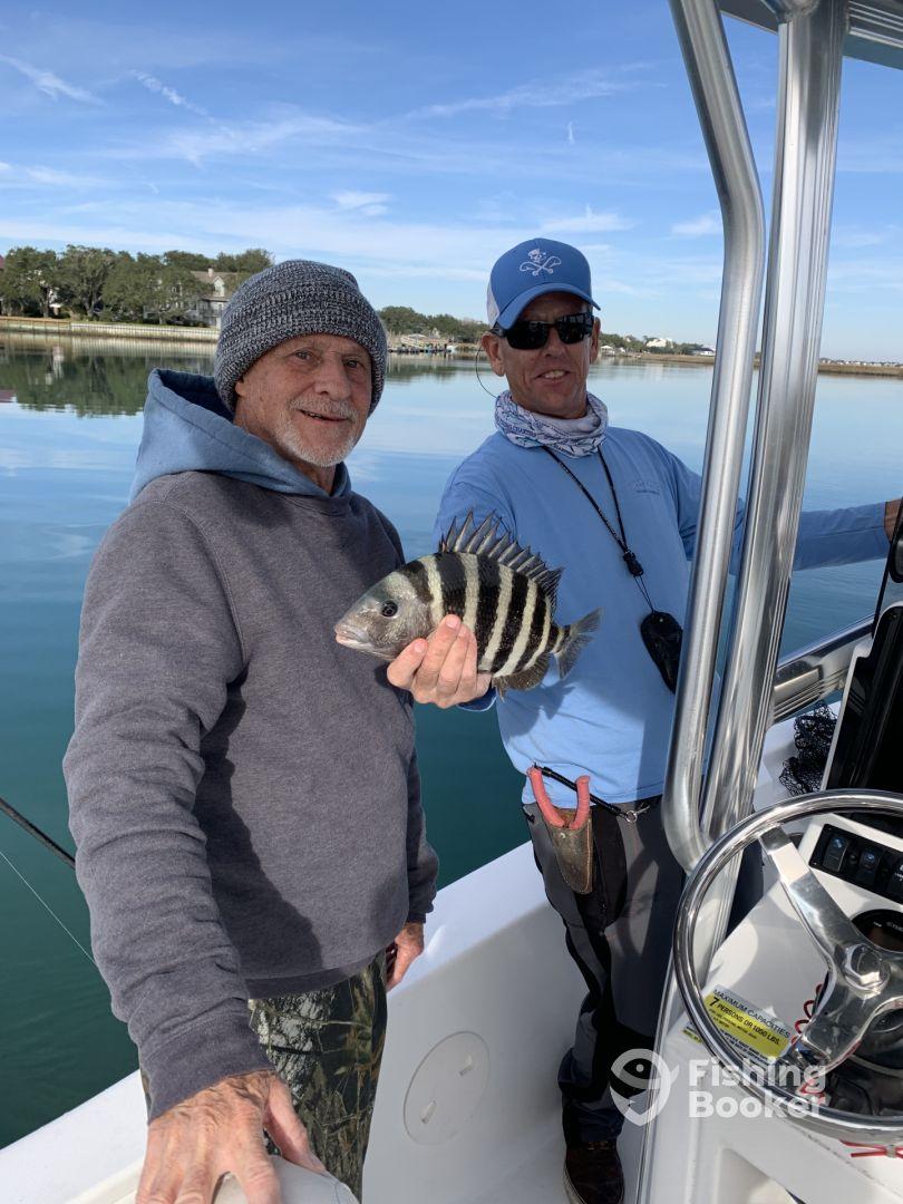 Two anglers proudly displaying a freshly caught Sheepshead aboard a fishing boat, with a calm water backdrop.