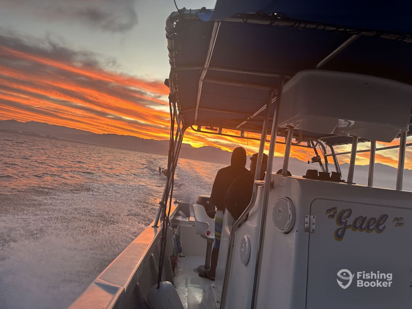 A scenic view of the boat 'Gael' cruising at sunset, showcasing the beautiful colors of the sky and the calm waters.