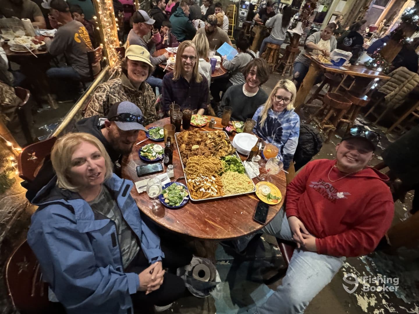 A group of friends enjoying a meal together in a lively restaurant setting, with various dishes on the table.