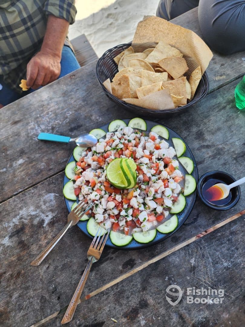 A vibrant plate of ceviche garnished with lime and served with tortilla chips, enjoyed by diners at a beachside table.