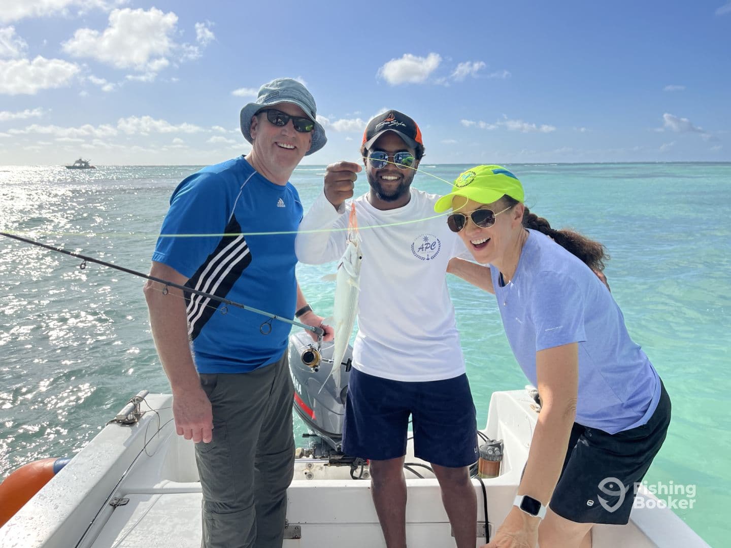 Two adults celebrating a catch while fishing on a boat in clear tropical waters, showcasing a lively fishing experience.