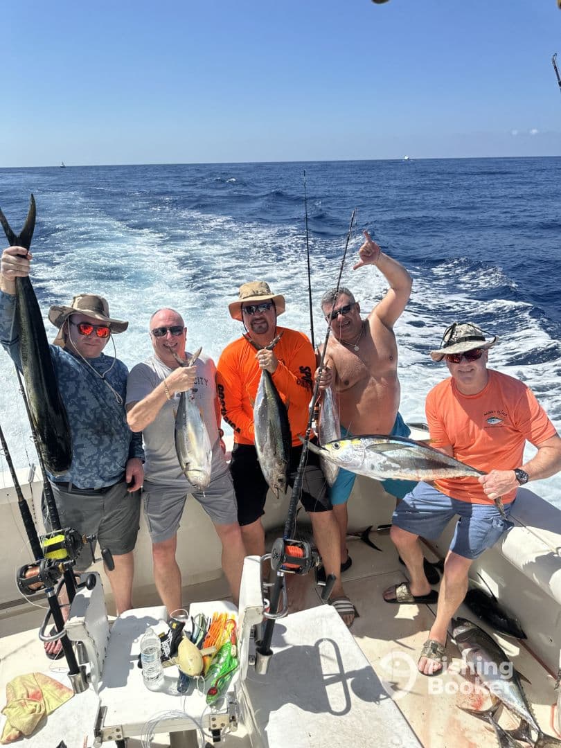 Group of anglers proudly displaying their catch of Mahi Mahi and Tuna aboard a sport fishing boat in open waters.