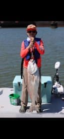 A young angler proudly displaying a large Redfish while fishing on a sunny day.