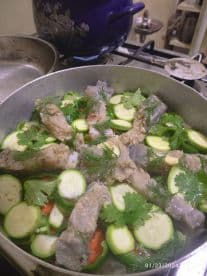 A pot of fish and vegetables simmering on a stove, showcasing a home-cooked meal preparation.