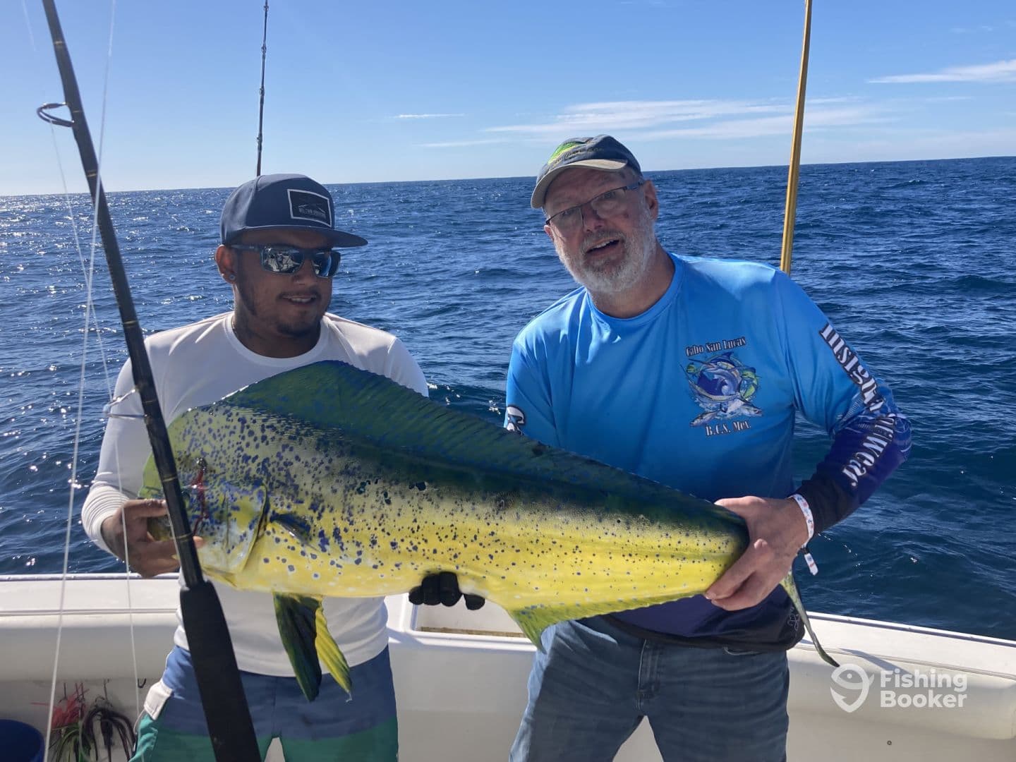 Two anglers proudly displaying a large Mahi-Mahi while fishing offshore, showcasing the vibrant colors of the catch against a clear blue ocean backdrop.
