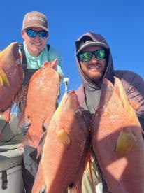 Two anglers proudly displaying their catch of colorful Snapper while out on a sunny fishing trip.