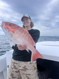 Angler proudly displaying a large Red Snapper while fishing offshore, showcasing the excitement of a successful catch.