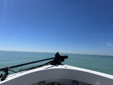 A clear view from the front of the boat, showcasing the calm waters and bright blue sky, ideal for a day of fishing.