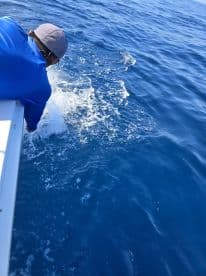 An angler actively reeling in a fish while fishing in deep blue waters, showcasing the excitement of the catch.