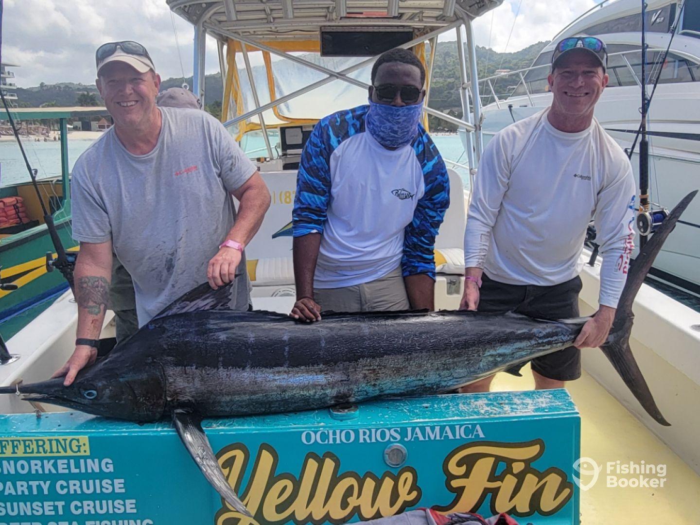 Three anglers proudly displaying a large Yellowfin Tuna aboard a fishing charter in Ocho Rios, Jamaica.