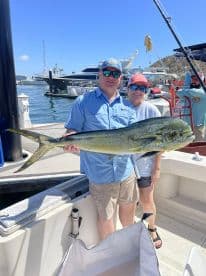 Two anglers proudly displaying a large Mahi Mahi at the marina after a successful fishing trip.