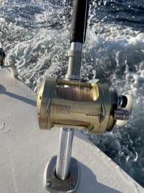 Close-up of a Shimano Tiagra 50W fishing reel mounted on a boat, showcasing the fishing gear in action on the water.