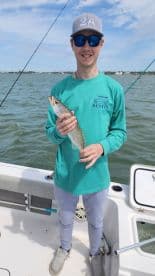 Young angler proudly holding a Speckled Trout while fishing in Destin, showcasing a successful day on the water.