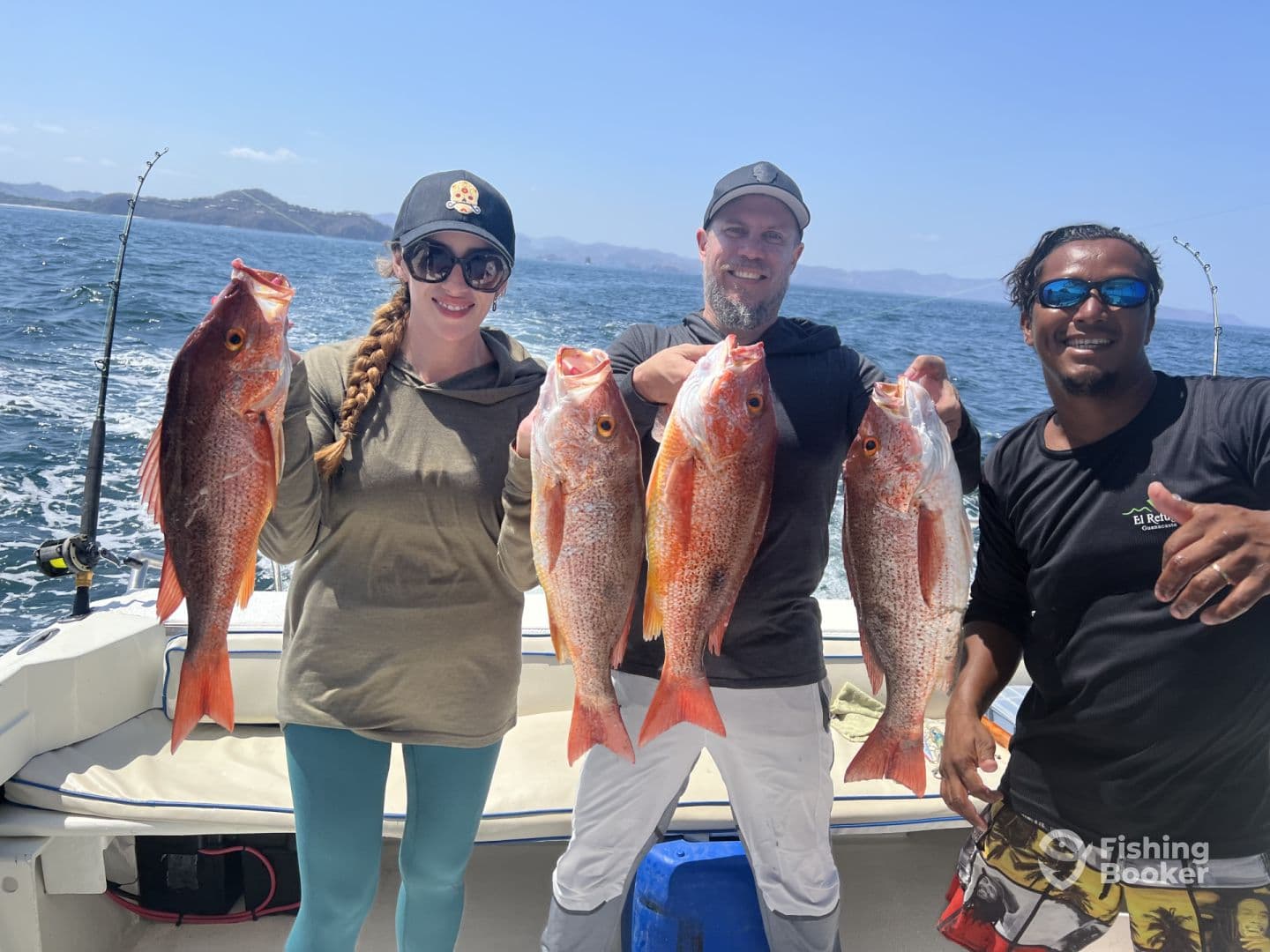 Three anglers proudly displaying their catch of Red Snapper while aboard a fishing boat in a sunny coastal environment.
