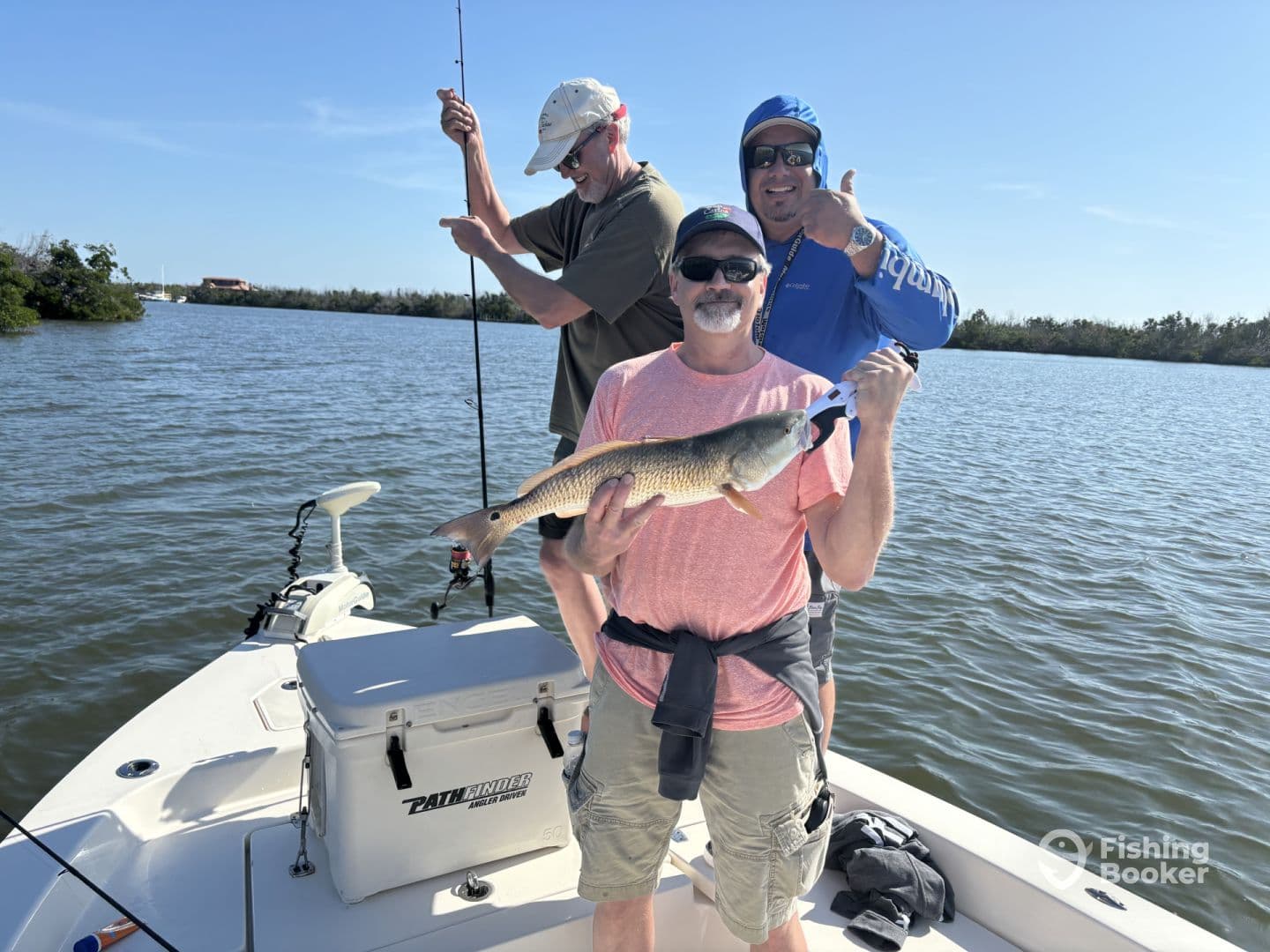 A group of anglers enjoying a successful day on the water, with one proudly displaying a Redfish caught during their fishing trip.
