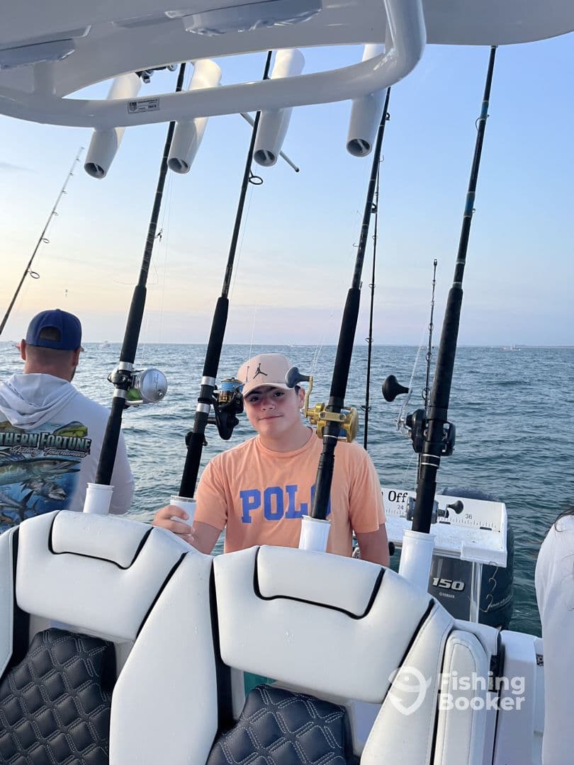 A young angler enjoying a fishing trip on a well-equipped boat, showcasing the comfortable seating and fishing rods in the background.