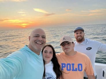 A group of four people enjoying a sunset on a fishing boat, capturing a memorable moment together.