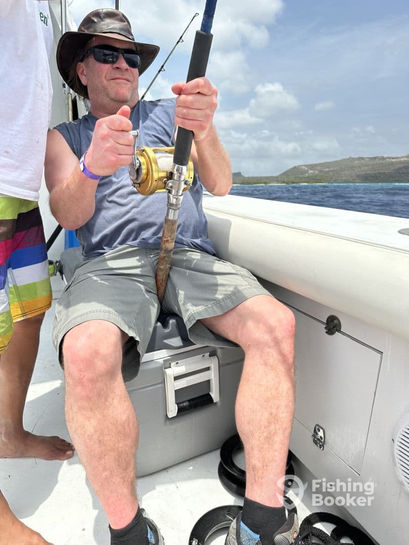 An angler actively reeling in a catch while seated on a fishing boat, showcasing the excitement of deep-sea fishing.