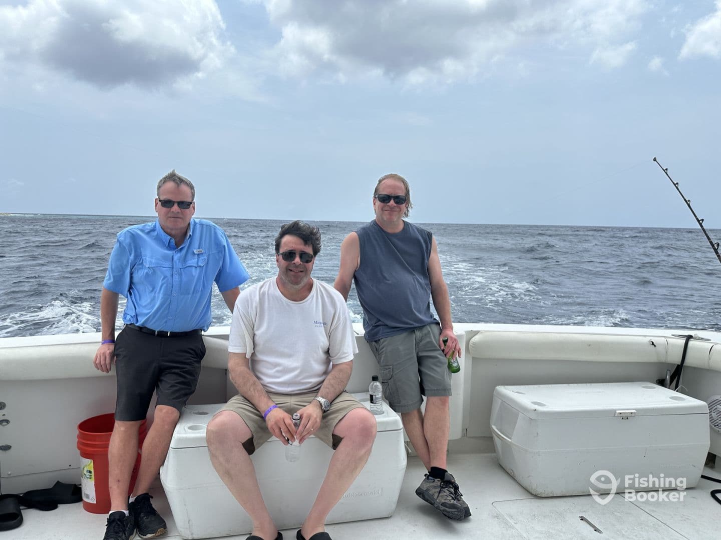 Three adult anglers relaxing on the deck of a sportfishing boat, enjoying a day out on the open water.