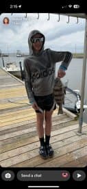 Young angler proudly displaying a striped bass on the dock, showcasing a successful fishing trip.