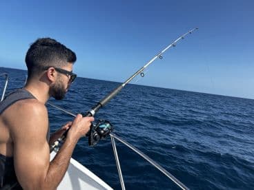 An angler focused on reeling in a catch while fishing offshore, showcasing the excitement of deep-sea fishing.