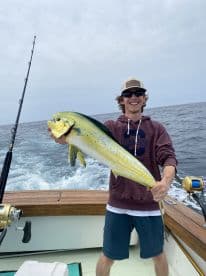 A young angler proudly displaying a vibrant Mahi-Mahi while fishing offshore, showcasing the excitement of a successful catch.