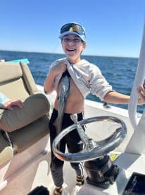 A young angler joyfully displaying a fish while aboard a boat, showcasing the excitement of a fishing adventure.