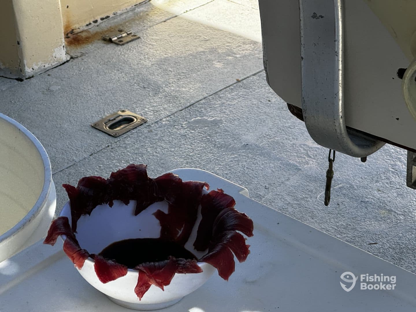 A bowl filled with freshly cut fish fillets resting on the deck of a fishing boat, showcasing the preparation process after a successful catch.