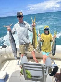 A proud angler and a young fisherman displaying their catch of Mahi Mahi and a Wahoo while enjoying a day on the water.