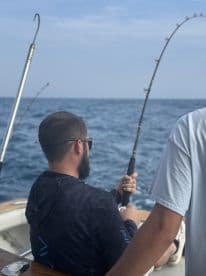 Angler actively reeling in a catch while fishing offshore, showcasing the excitement of deep-sea fishing.